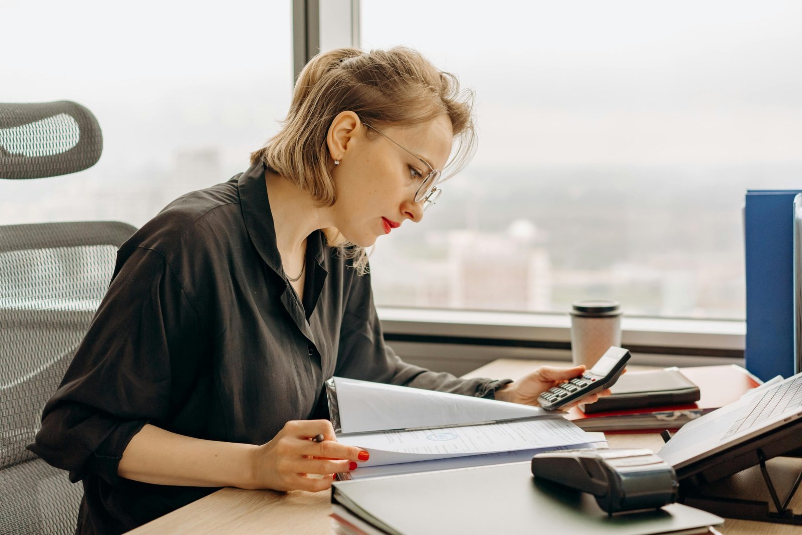 Woman accountant calculating financial documents at office desk.